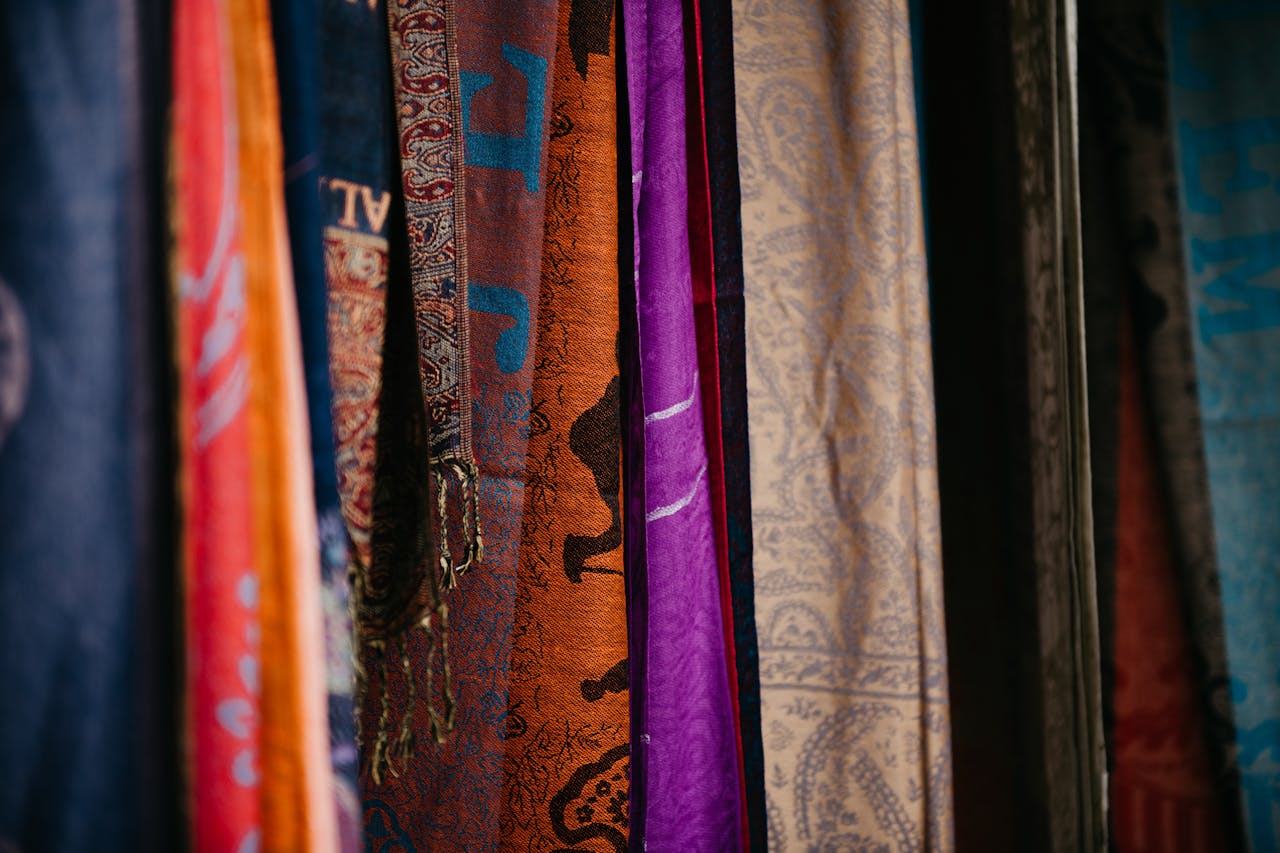 Colorful textiles on display at an indoor market stall in Nazareth, showcasing rich designs and textures.