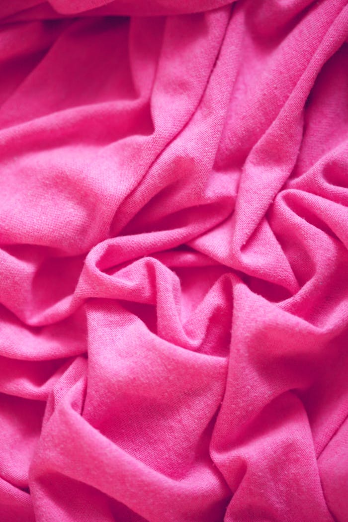 A close-up of soft, wrinkled pink fabric, showcasing texture and softness.